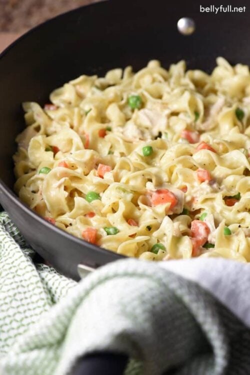 cooked egg noodles, peas, carrots, and chicken in skillet